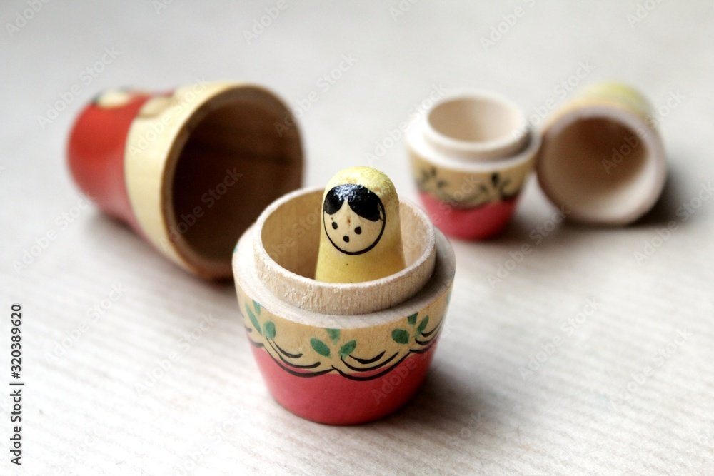 Wooden Russian matryoshka dolls in folk style, girls with painted dresses and veiled heads covered with babushka shawl. A little girl is lost, alone and frightened. It also resembles "story in a story" and what is this called. A nested story.